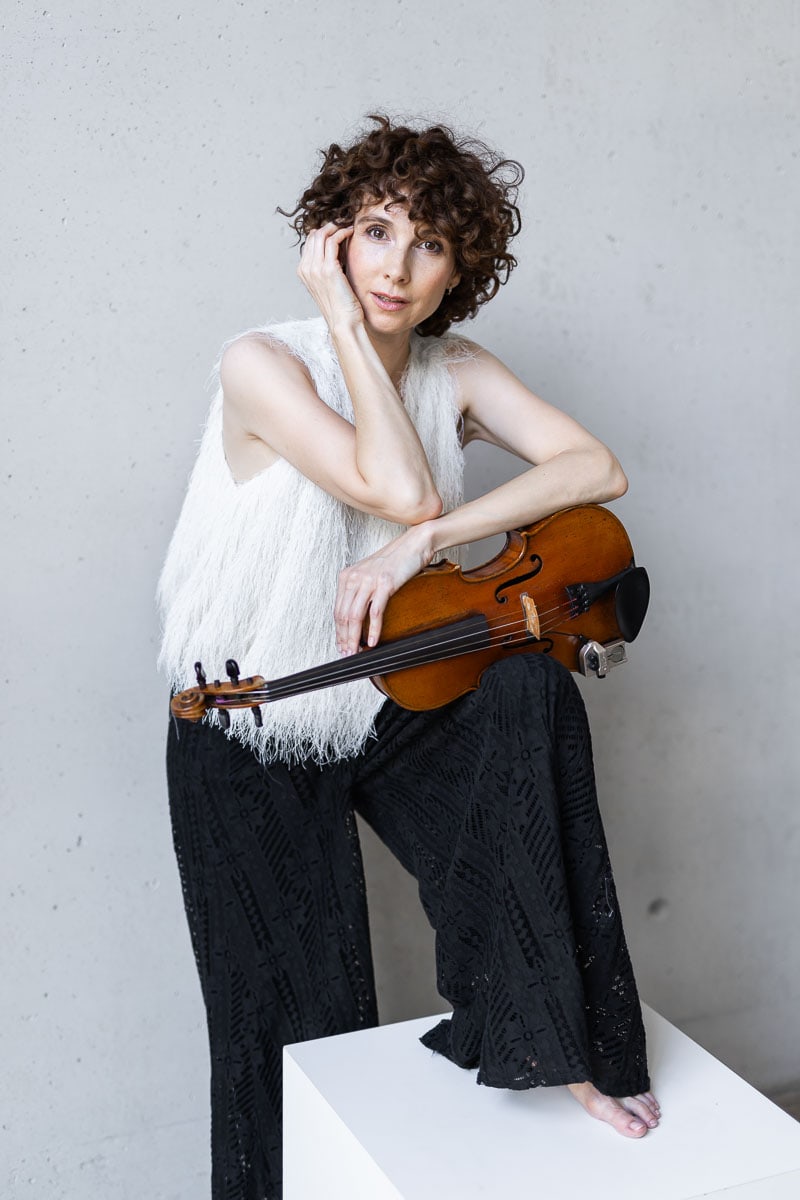 Frau mit Cello in modernem Studio, künstlerische Porträtaufnahme.