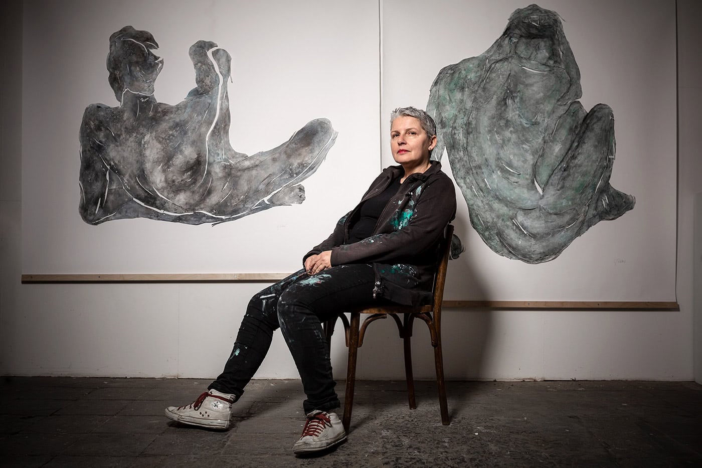 Frau sitzt vor modernen abstrakten Gemälden in einer Kunstgalerie in Köln.