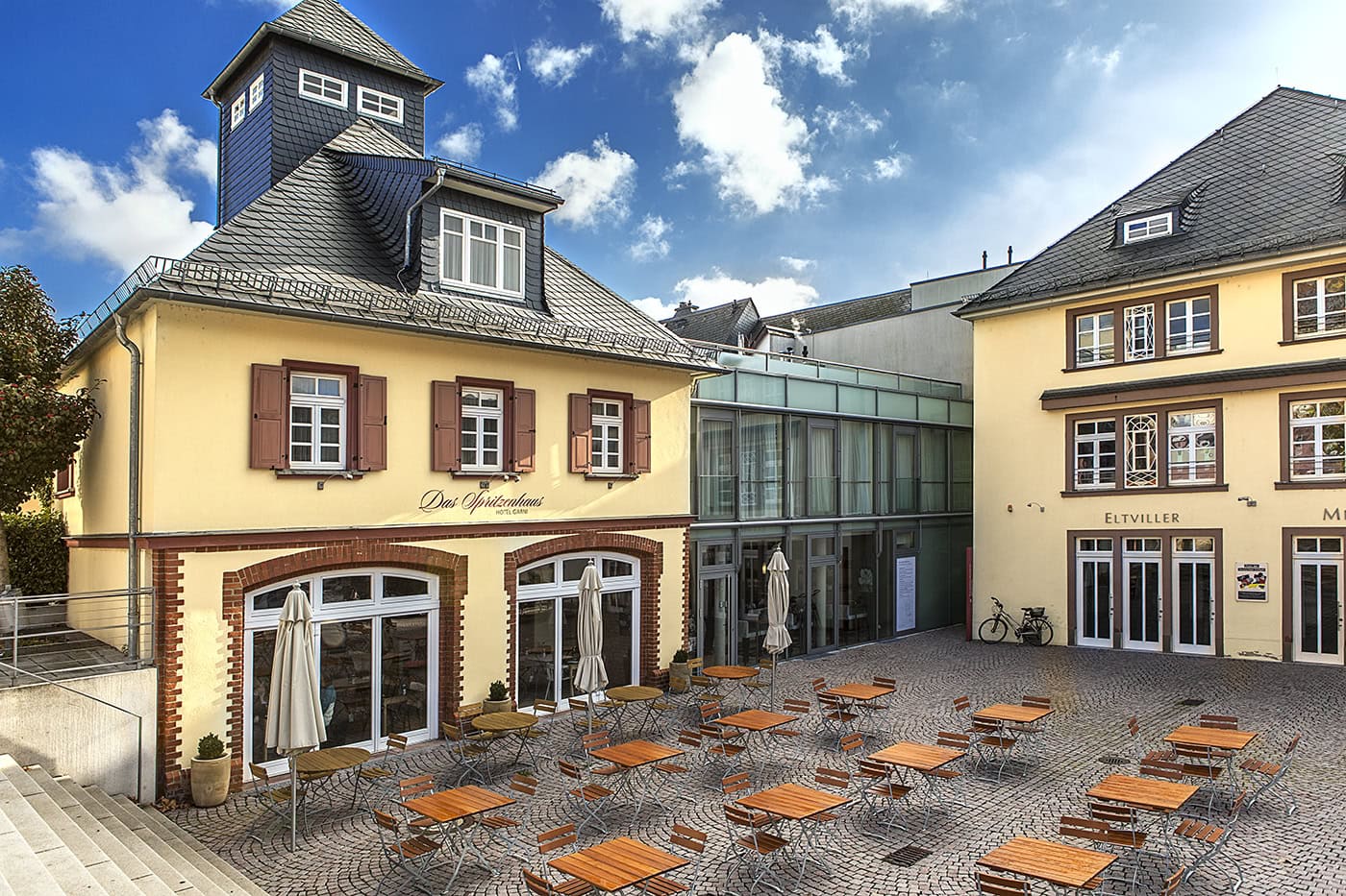 Historisches Gebäude in Köln mit Außenbestuhlung und moderner Glasfassade.