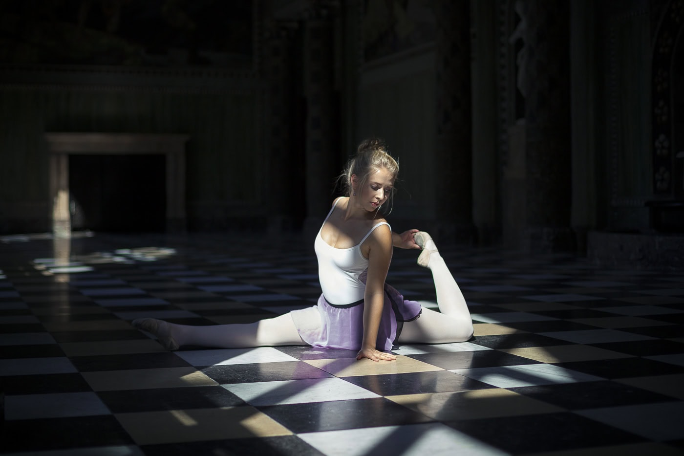 Tänzerin in Yoga-Pose auf schwarz-weißer Fliesen im Kirchenraum, professionelle Fotografie.