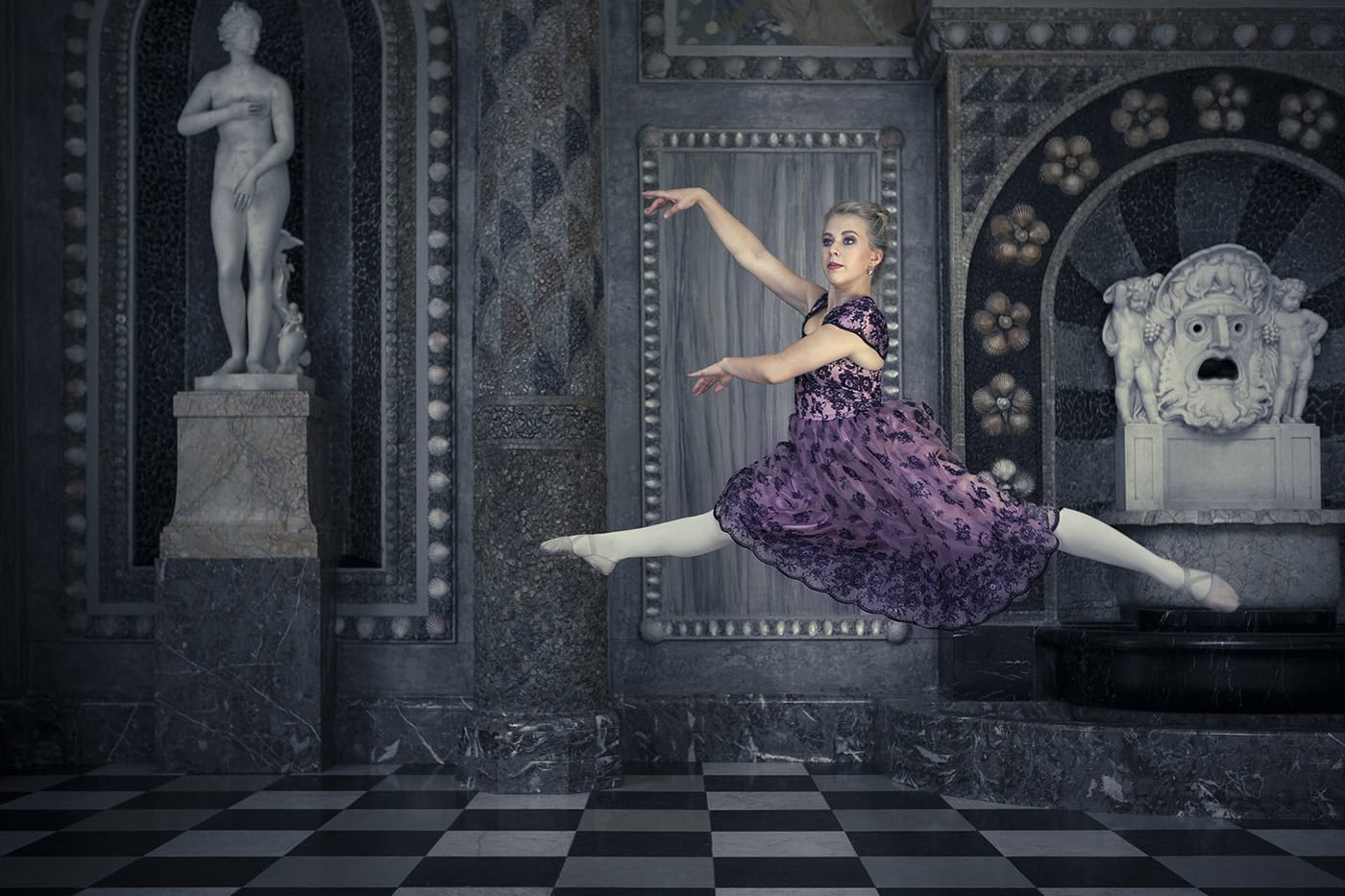 Balletttänzerin in Köln springt elegant vor einer kunstvollen Wand.