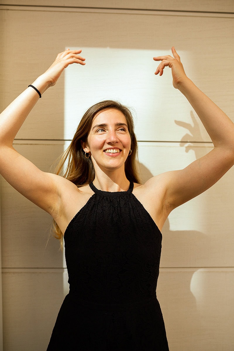 Fröhliche Frau in schwarzem Kleid, lächelnd, bei Fotoshooting in Köln.