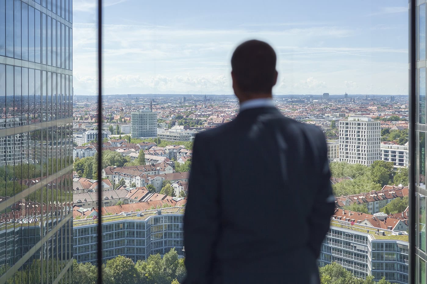 Businessmann blickt auf die Skyline von Köln von einem Hochhaus aus.