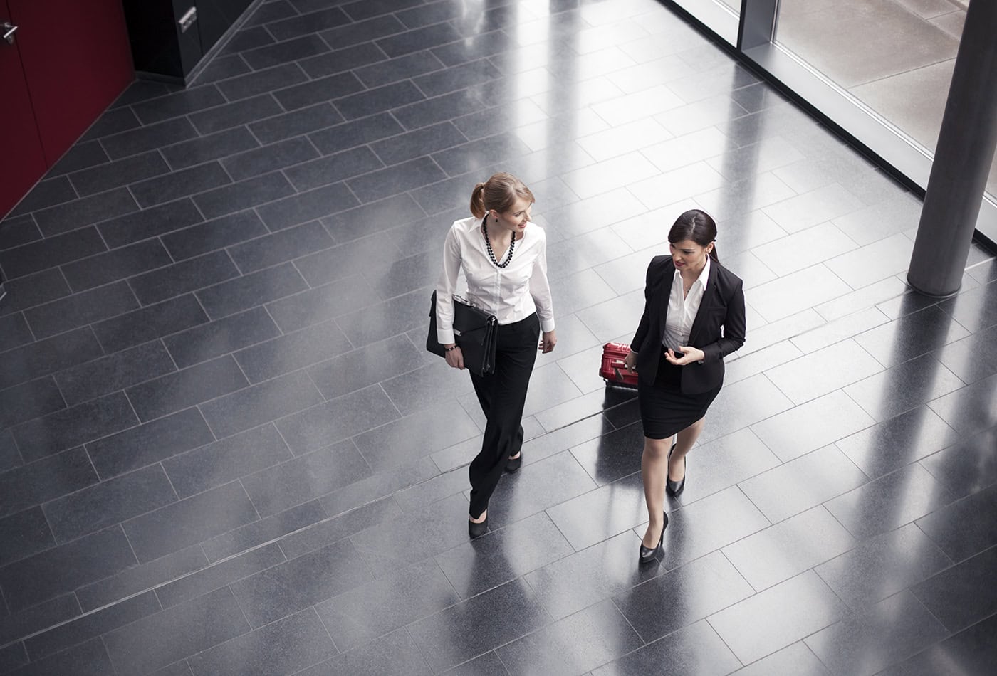 Zwei professionelle Frauen im Gespräch in moderner Business-Lobby.