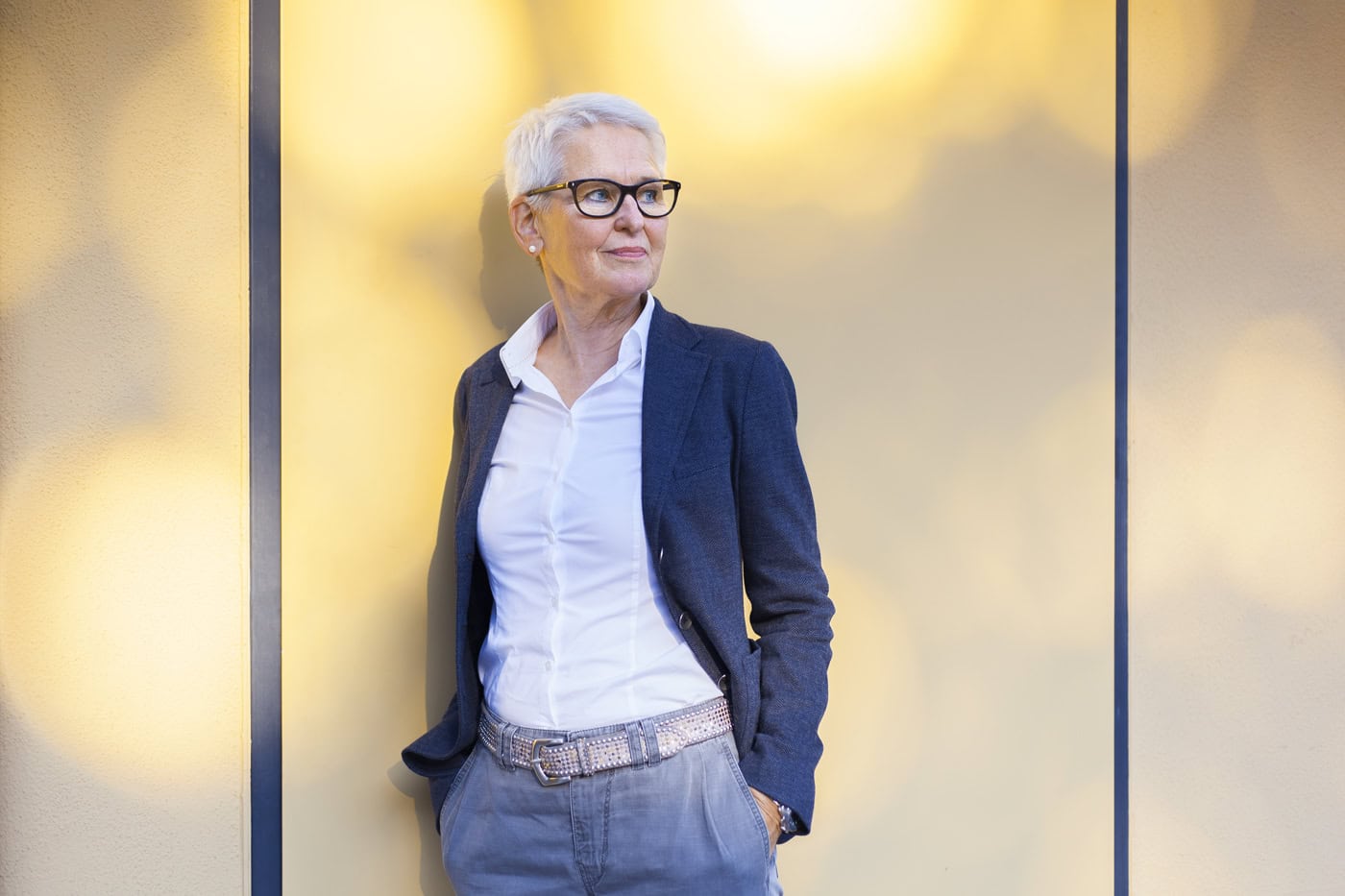 Porträt einer älteren Frau in Business-Kleidung vor modernem Hintergrund.