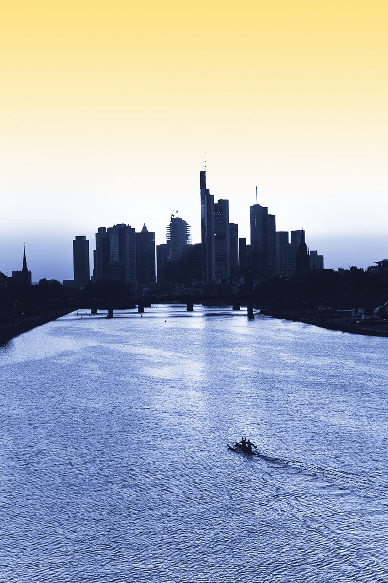 Skyline von Köln mit Fluss und Boot bei Sonnenuntergang.