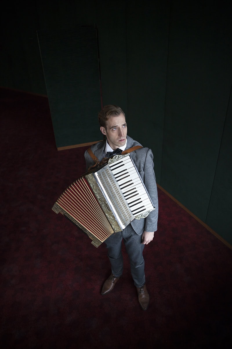 Mann mit Akkordeon in dunklem Raum, professionelle Musikfotografie in Köln.