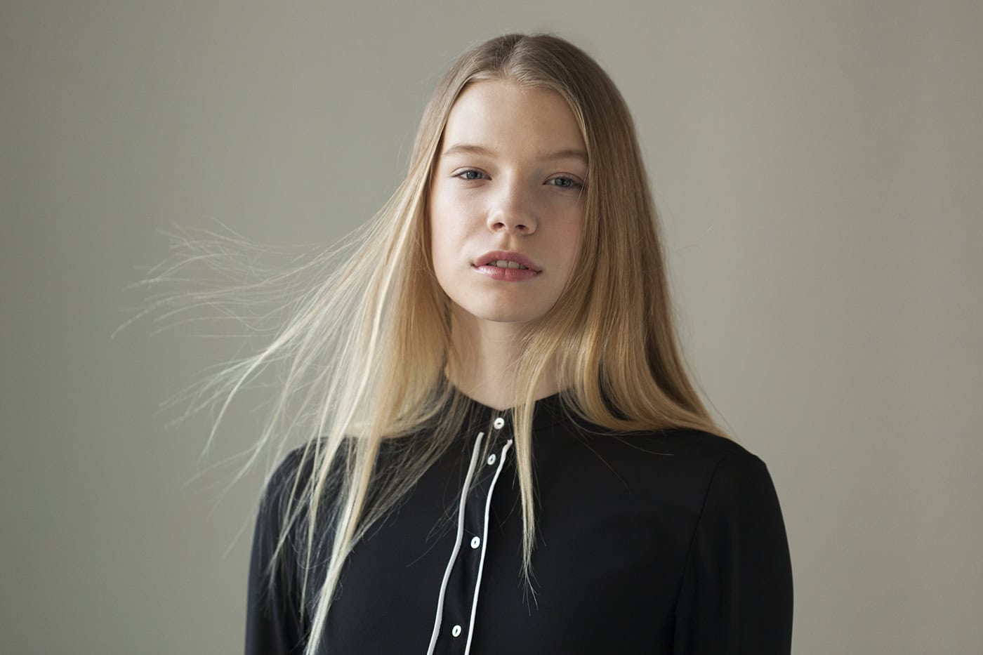 Porträt einer jungen Frau mit langen blonden Haaren, in schwarzem Oberteil, professionell fotografie.