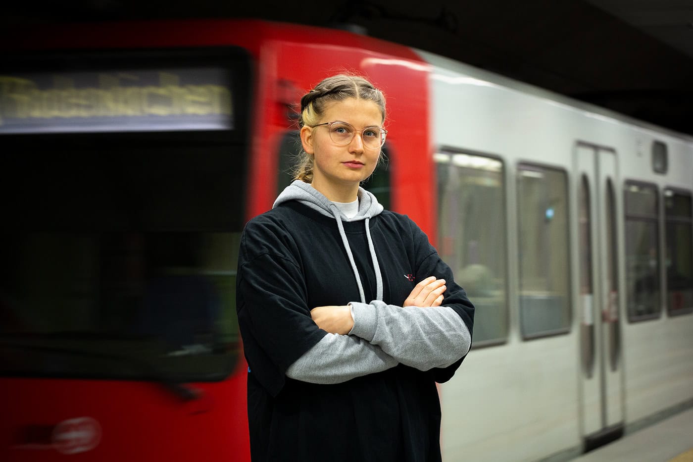 Junge Frau steht vor einer Straßenbahn in Köln, urbanes Stadtbild, professionelle Fotografie.