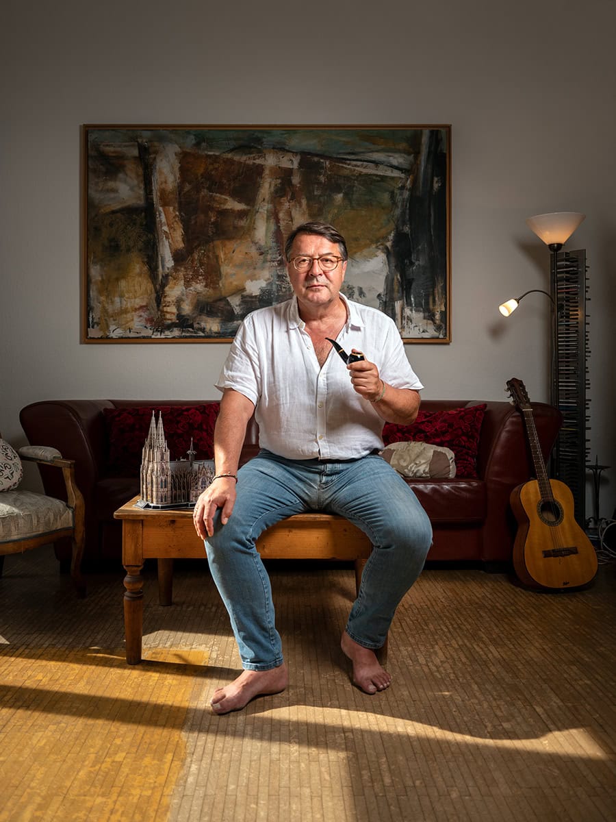 Porträt eines Mannes im Wohnzimmer mit Gitarre.