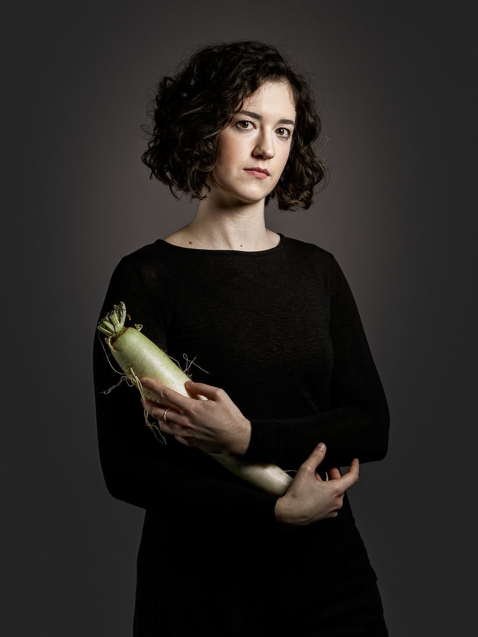 Porträt einer jungen Frau in Schwarz mit Blumenstrauß in den Händen.
