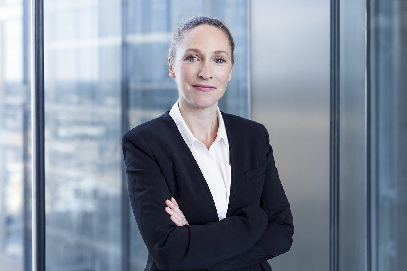 Professionelles Business-Porträt einer Frau in Anzug vor Glasfassade in Köln.