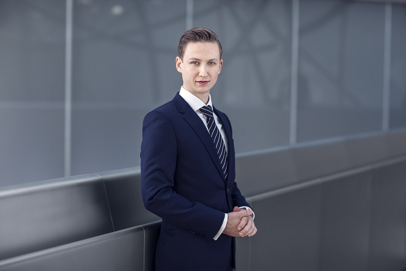 Professionelles Business-Porträt eines Mannes in Anzug vor moderner Architektur.