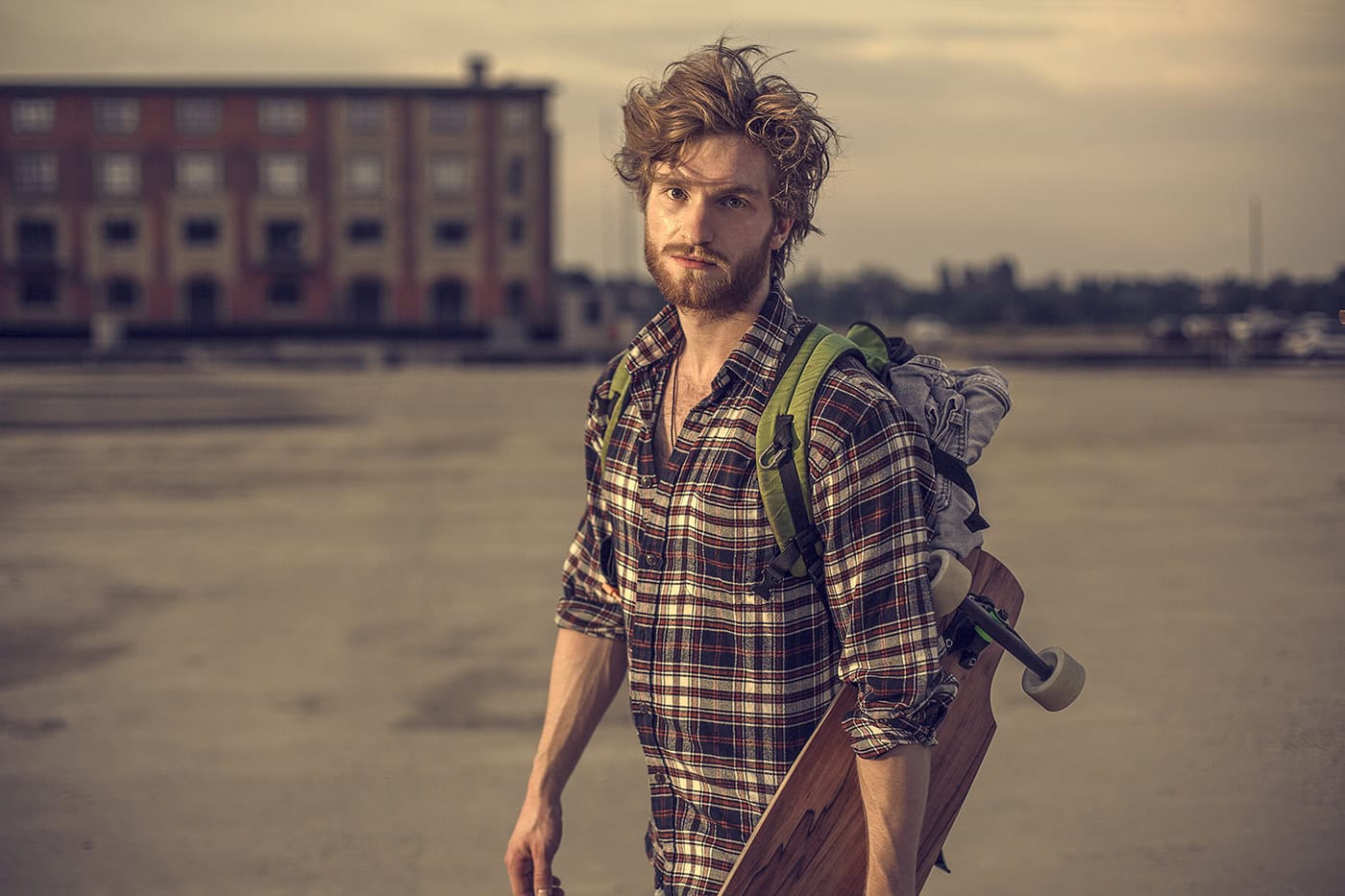 Junge Mann mit Rucksack und Skateboard in Stadtlandschaft, Naturfotografie.