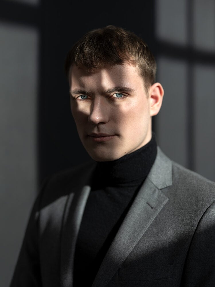 Porträtfotografie eines jungen Mannes in dunklem Anzug.