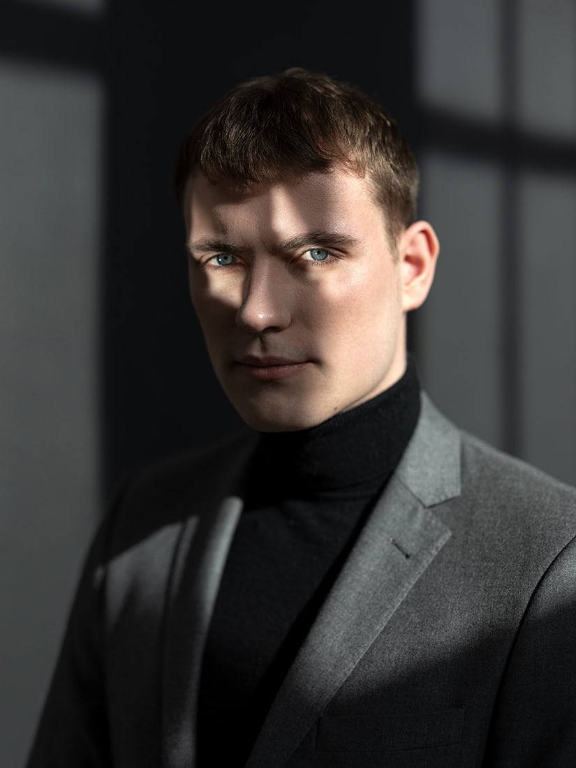 Porträtfotografie eines jungen Mannes in dunklem Anzug.