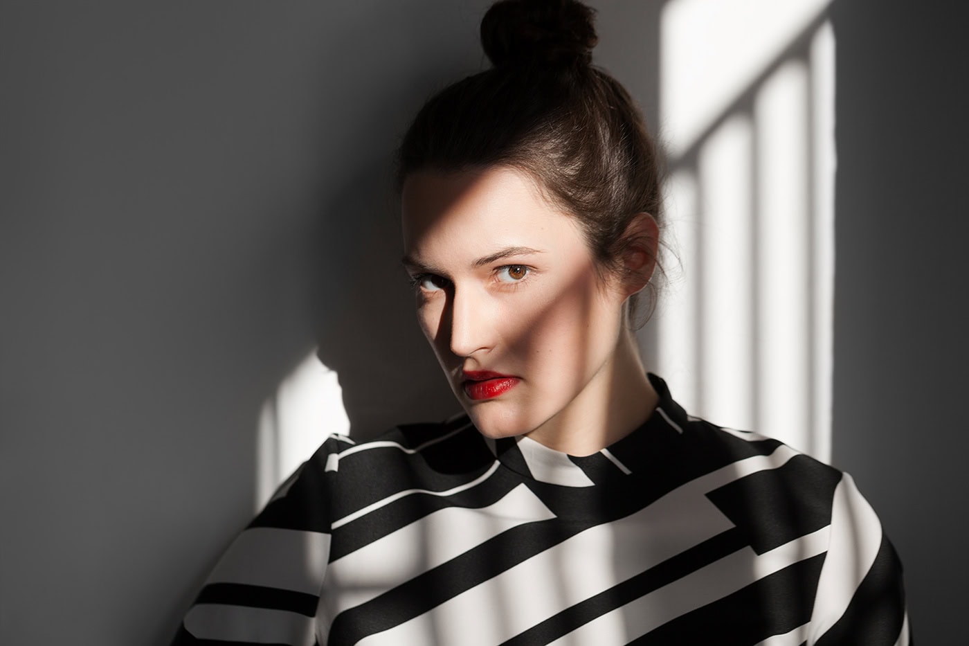 Frau in Schwarz-Weiß-Kleid mit Schatteneffekt, professionelle Portraitaufnahme in Köln.