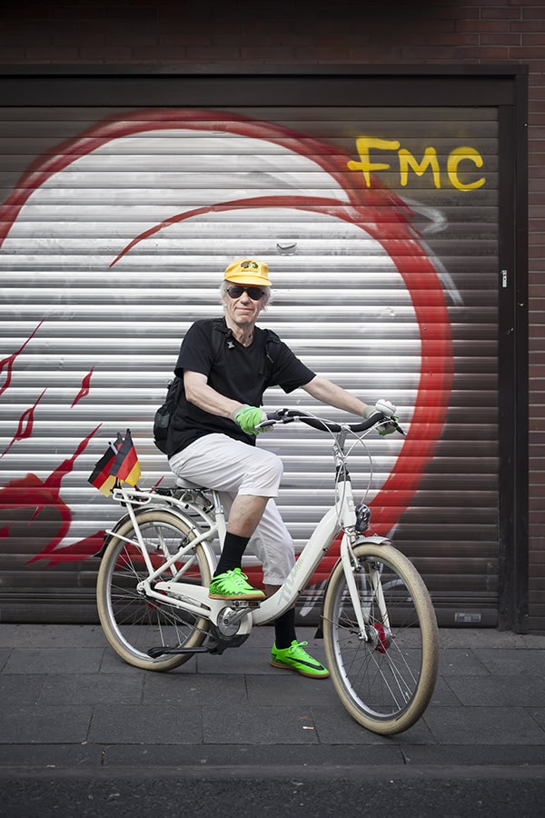 Fotograf mit Fahrrad vor Graffiti-Wand in Köln.