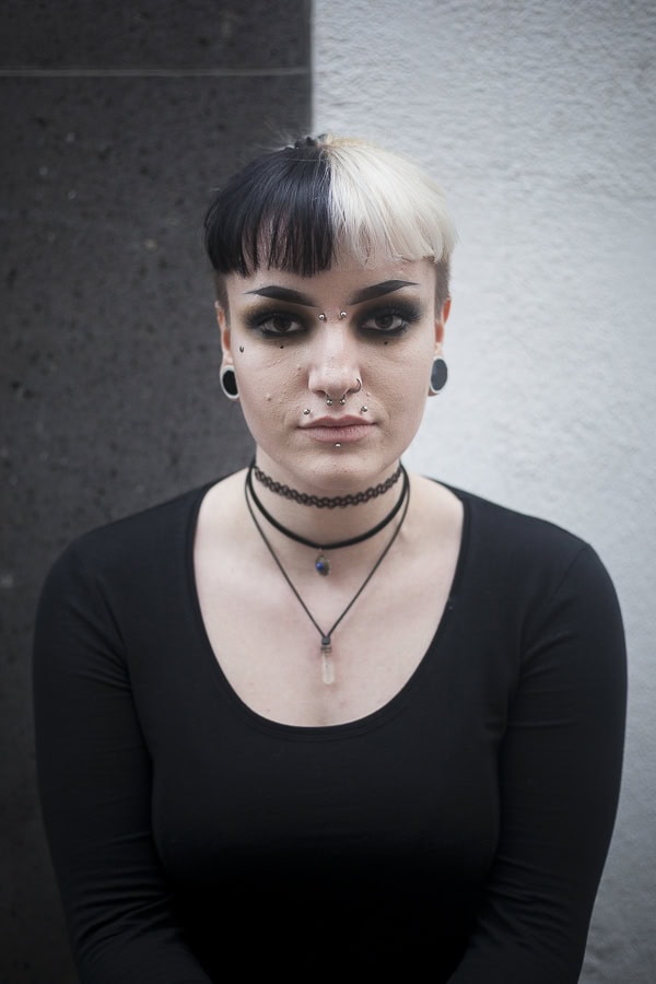 Ausdrucksstarkes Portrait einer jungen Frau mit Piercings und kurzen Haaren.