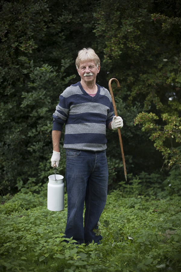 Älterer Mann mit Gehstock und Wasserkanister im Grünen.