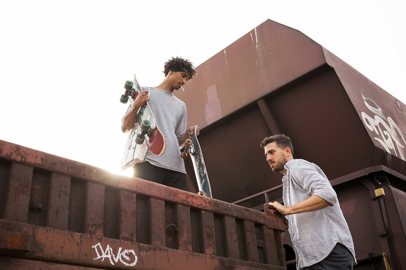 Zwei junge Männer mit Skateboards auf einem alten Güterwagen in Köln, urbanes Fotografie-Setting.