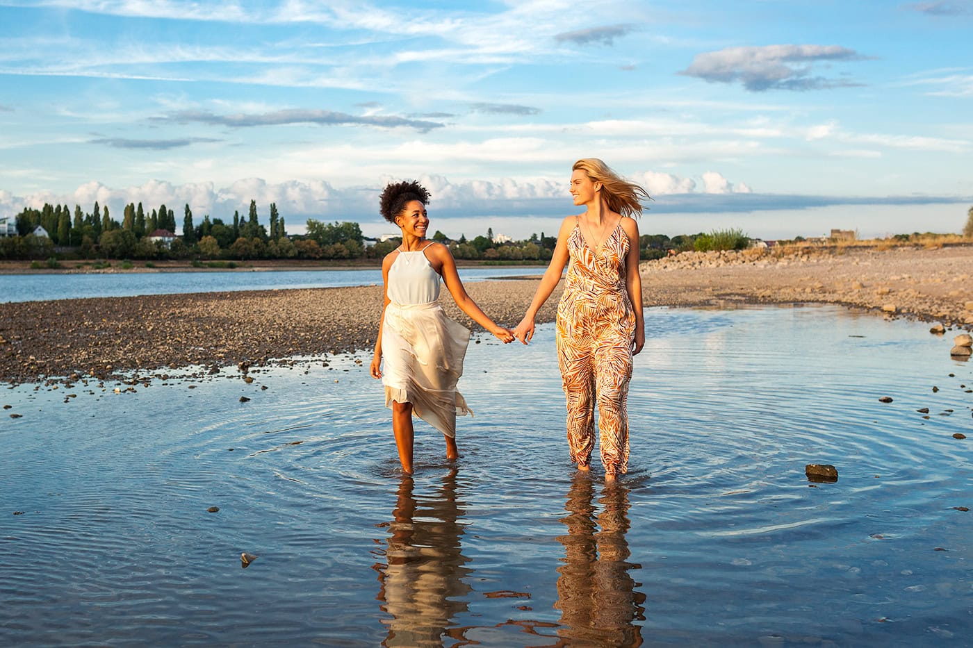 Zwei Frauen beim Spaziergang am Flussufer, Natur- und Lifestyle-Fotografie.