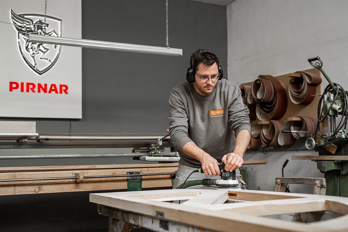 Handwerker beim Schleifen eines Holzrahmens in der Werkstatt.