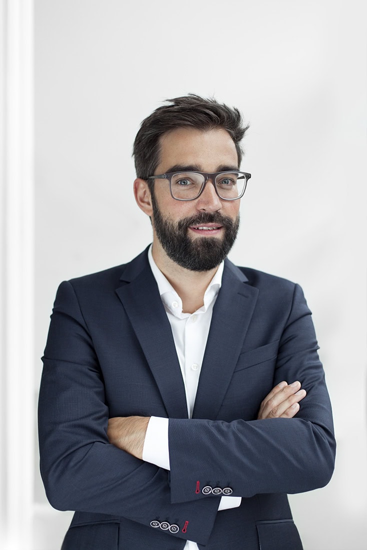 Geschäftsmann in Anzug mit Brille, professionell und selbstbewusst.