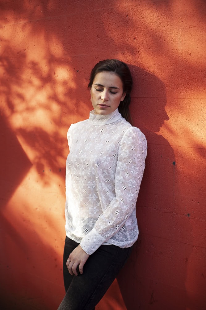 Frau in weißer Bluse vor roter Wand, professionelle Fotografie, Köln.
