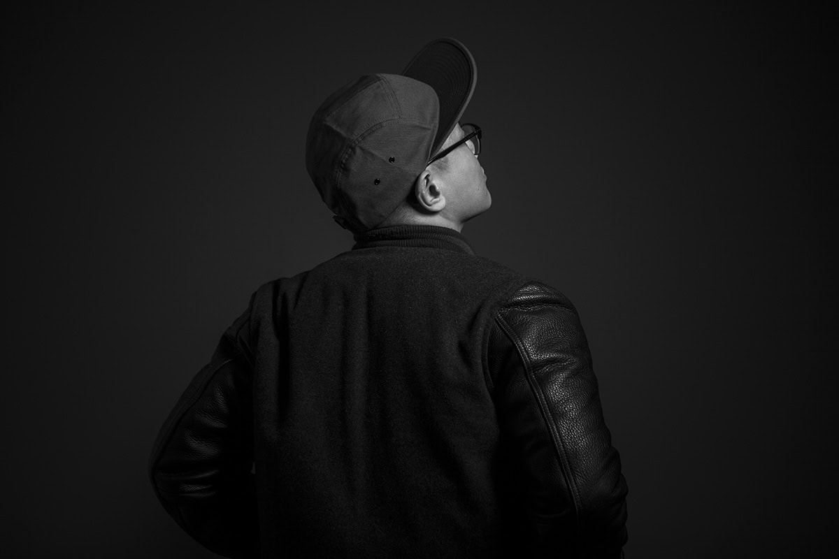 Fotografie eines Mannes in Schwarz-Weiß, seitlich betrachtet, mit Cap und Brille.