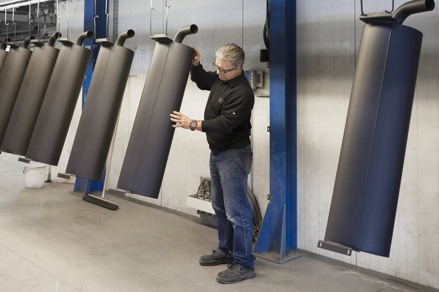 Mann inspiziert schwarze Solarmodule in einer Fabrikhalle, professionelle Produktfotografie.