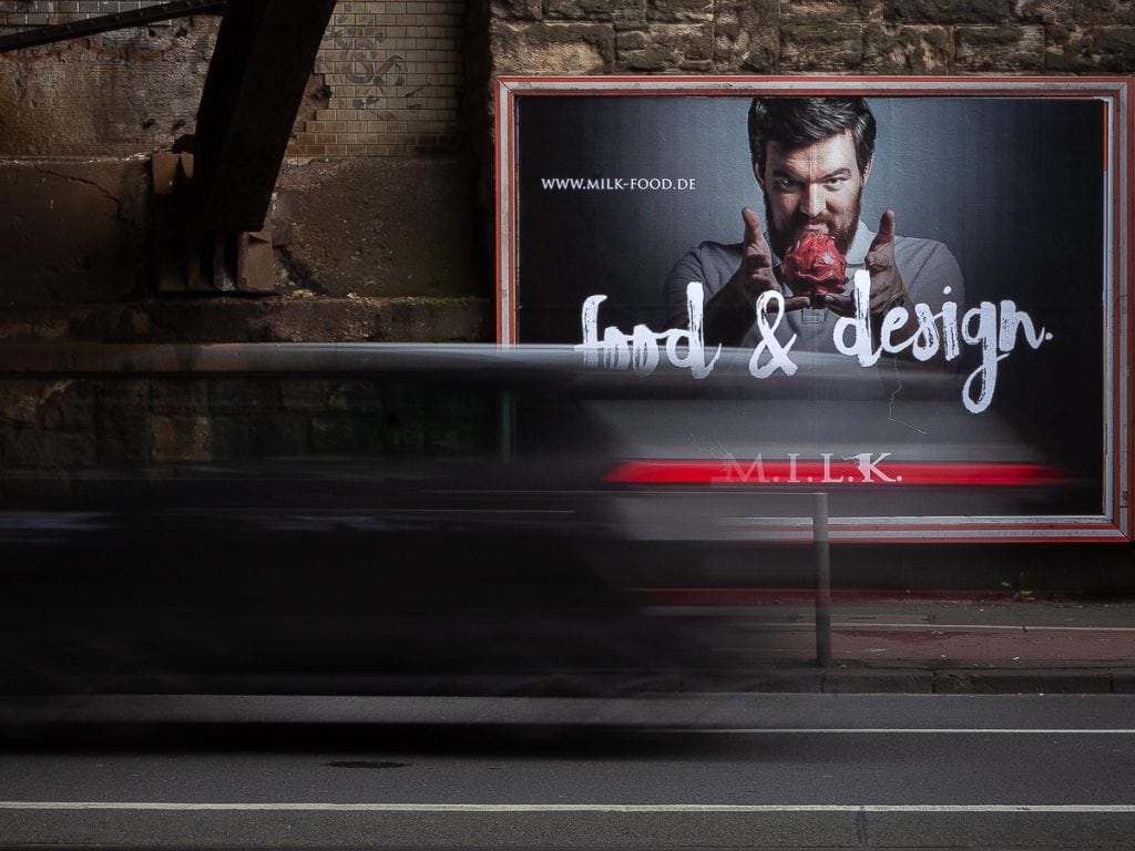 Werbeplakat mit Mann, der einen Burger hält, in Köln.