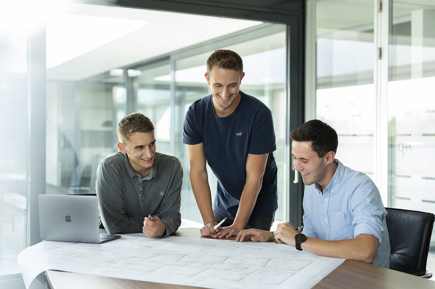Drei junge Männer bei einem Business-Meeting in einem modernen Konferenzraum in Köln.