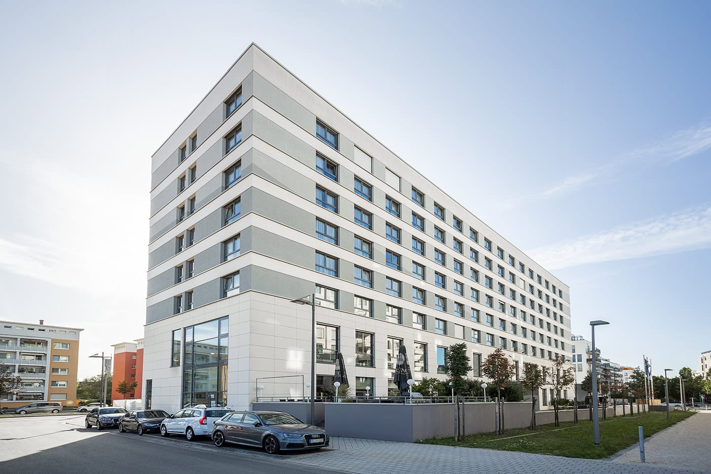 Modernes Bürogebäude in Köln mit Glasfassade und Parkplätzen.