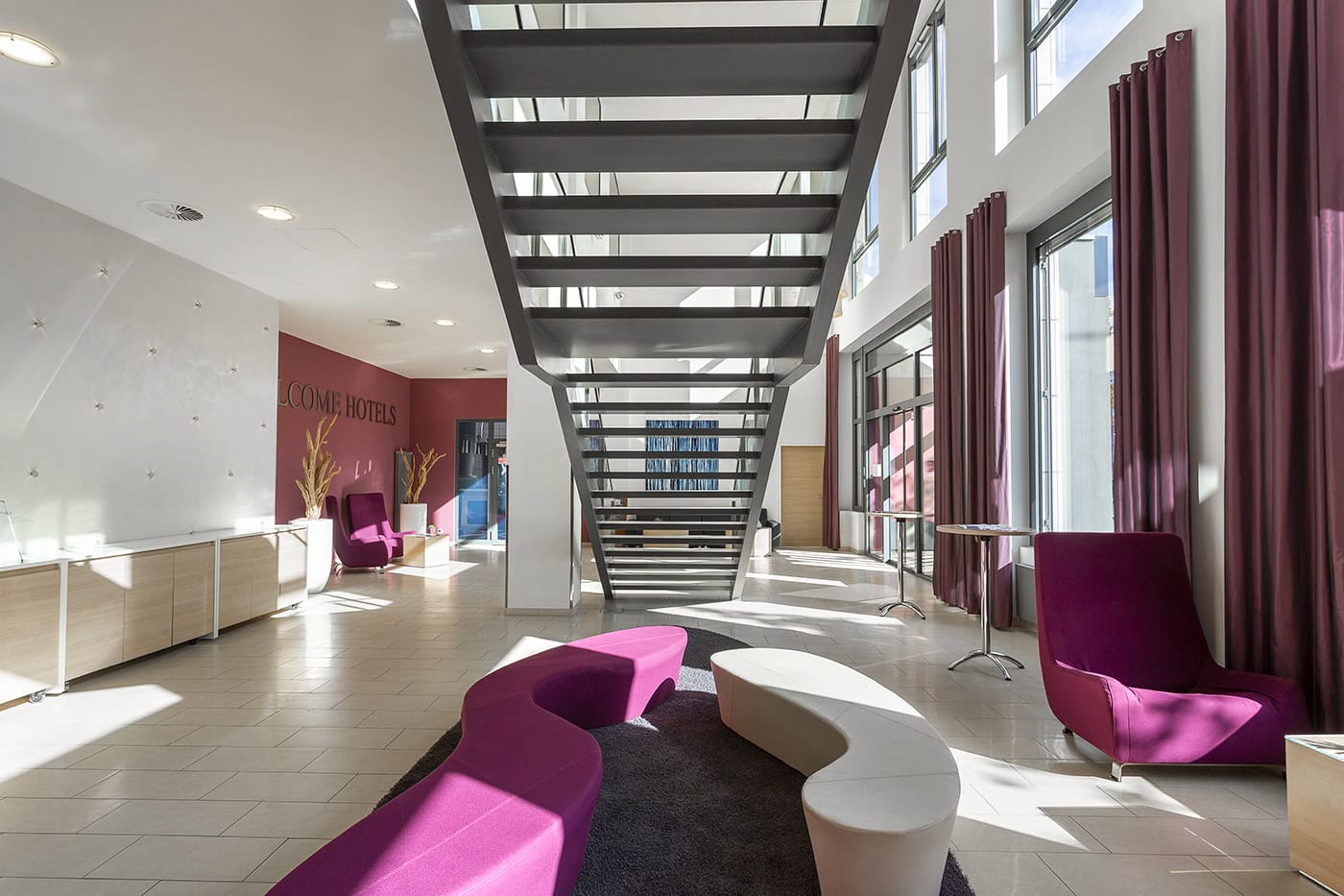 Helle Hotellobby mit modernen Sitzmöbeln und großem Fenster in Köln.