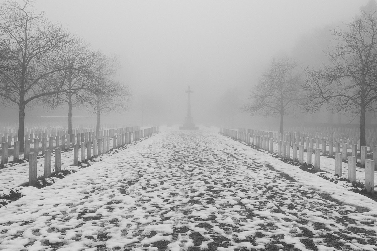 Winterliche Gedenkstätte mit Schneepfad, Nebel und Bäumen in Köln.