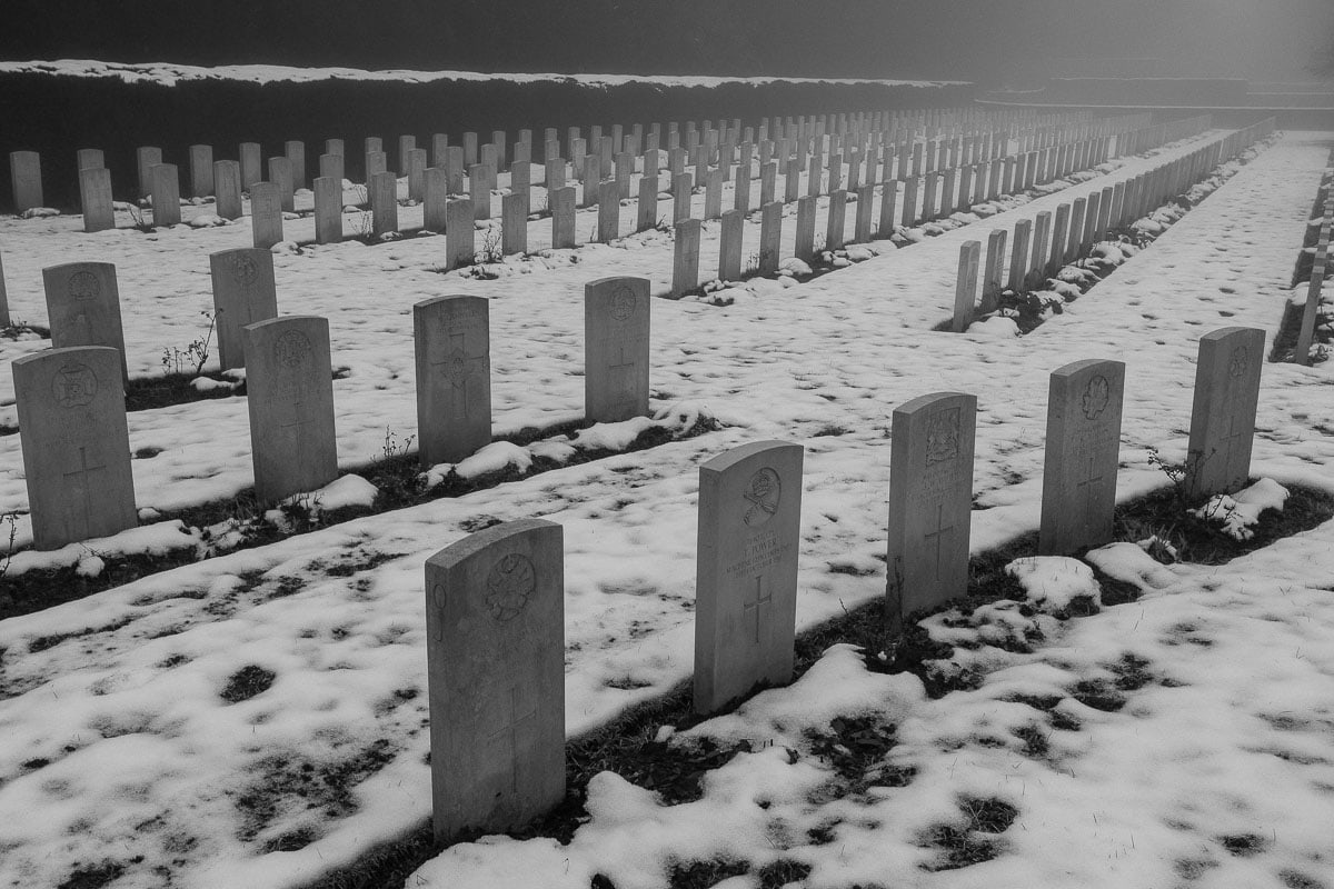 Schwarzer und weißer Friedhof mit Reihen von Gräbern im Schnee.