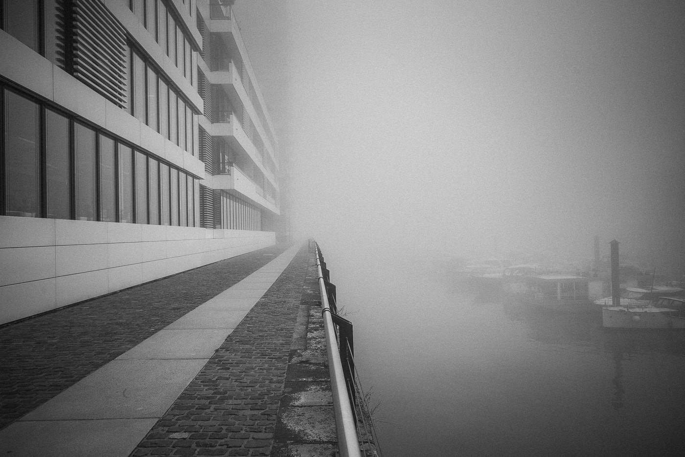 Blick auf eine moderne Gebäudefront am Wasser in Köln, nebliges Wetter.