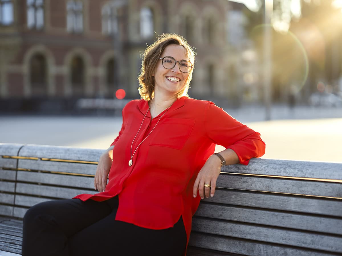 Fotografie von Frau in rotem Hemd auf Bank in Köln bei Sonnenuntergang.