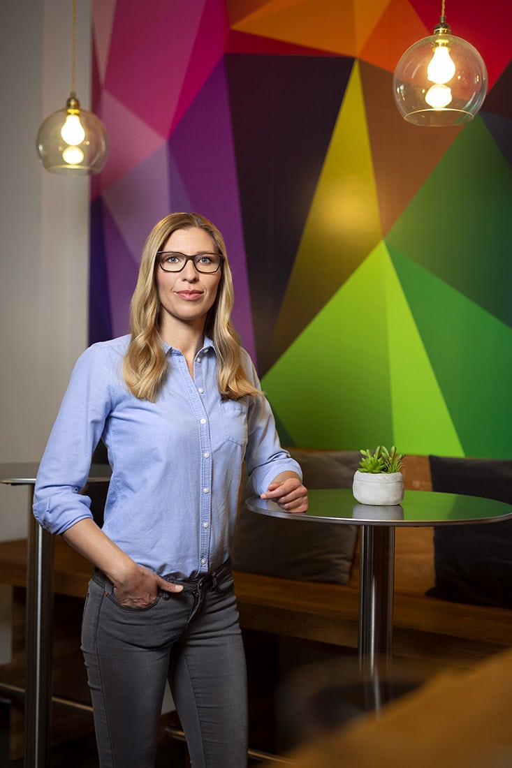 Hochwertiges Business-Porträt einer Frau in einem kreativen, bunten Raum.