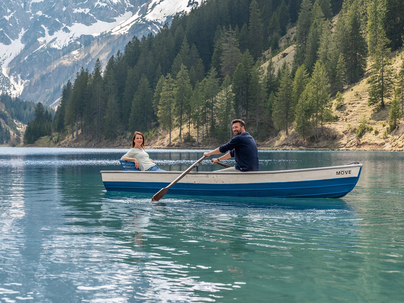 Paar beim Bootfahren auf einem klaren Bergsee in den Alpen.