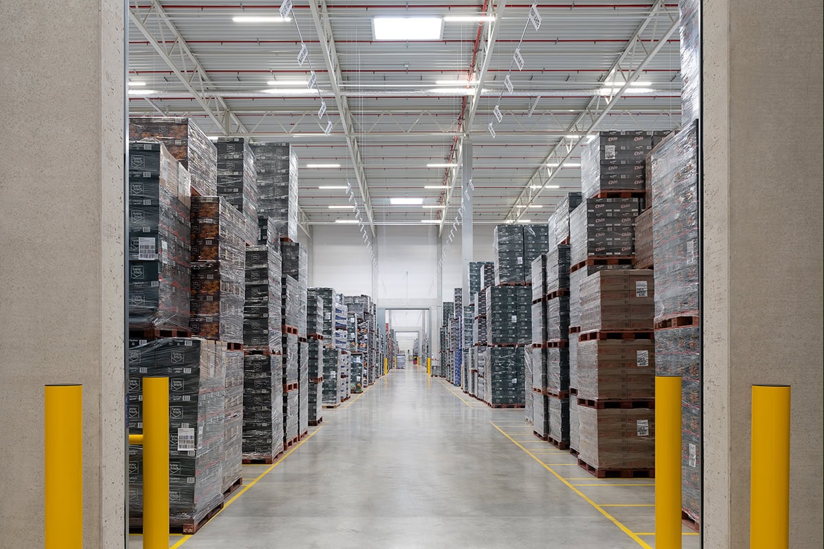 Lagerhalle mit hohen Regalen und Paletten in einem modernen Logistikzentrum.