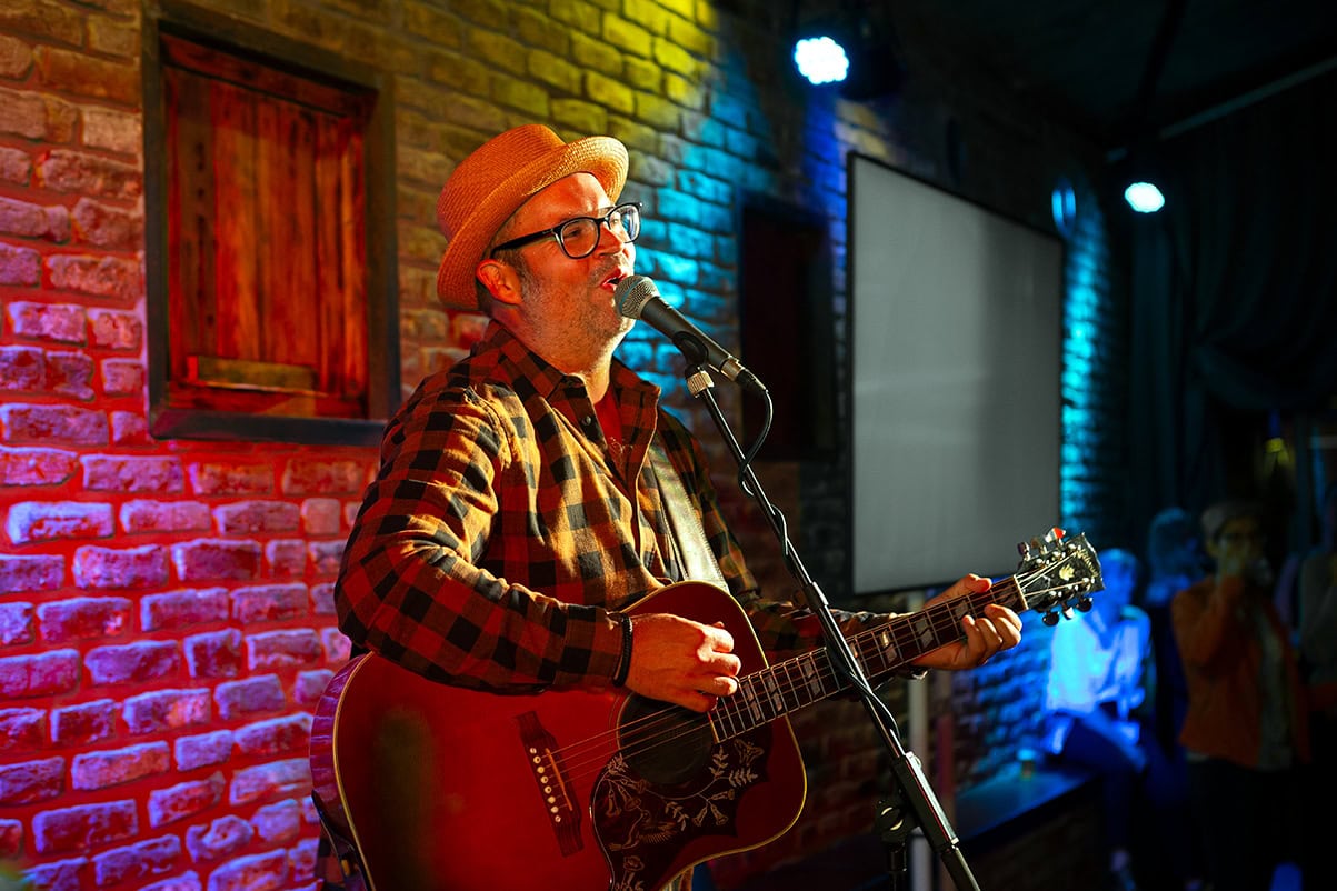 Musiker mit Gitarre und Hut bei Live-Performance in Köln, kreative Fotografie.