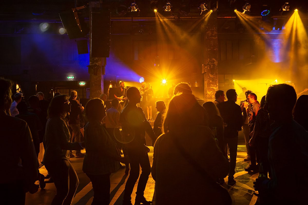 Menschen tanzen bei einer Party mit bunten Lichtern in einem Club.
