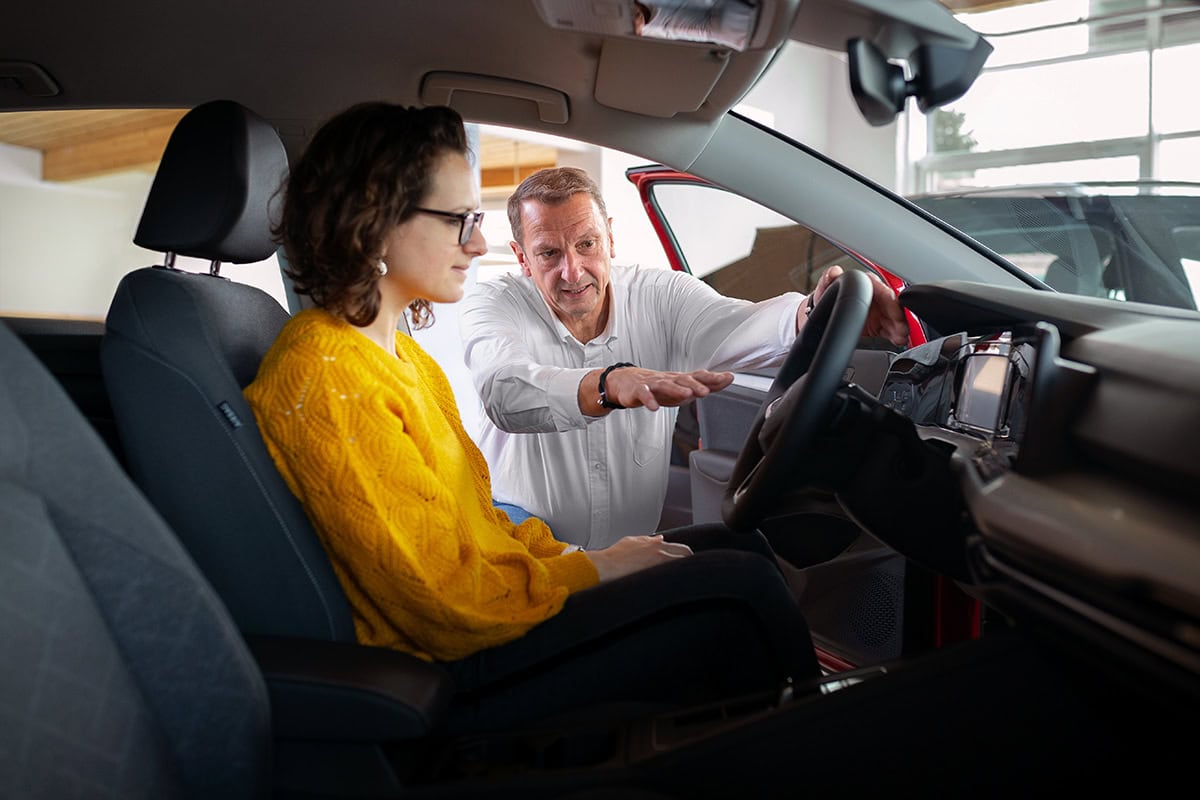 Fahrlehrer erklärt einer Frau im Auto Fahrtechnik in Köln.