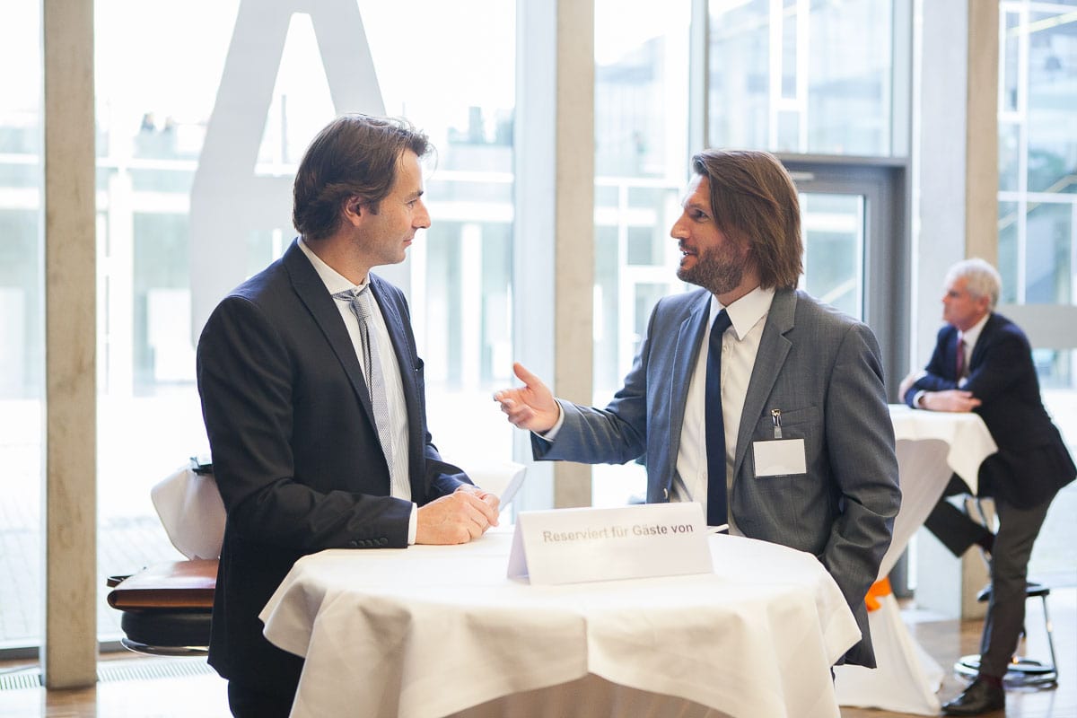 Zwei Geschäftsleute im Gespräch bei einer Konferenz in Köln.