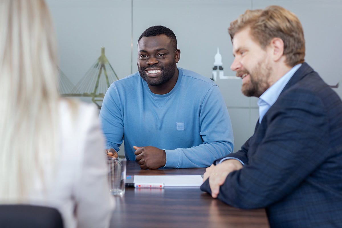 Geschäftstreffen mit drei Personen in einem modernen Büro in Köln.