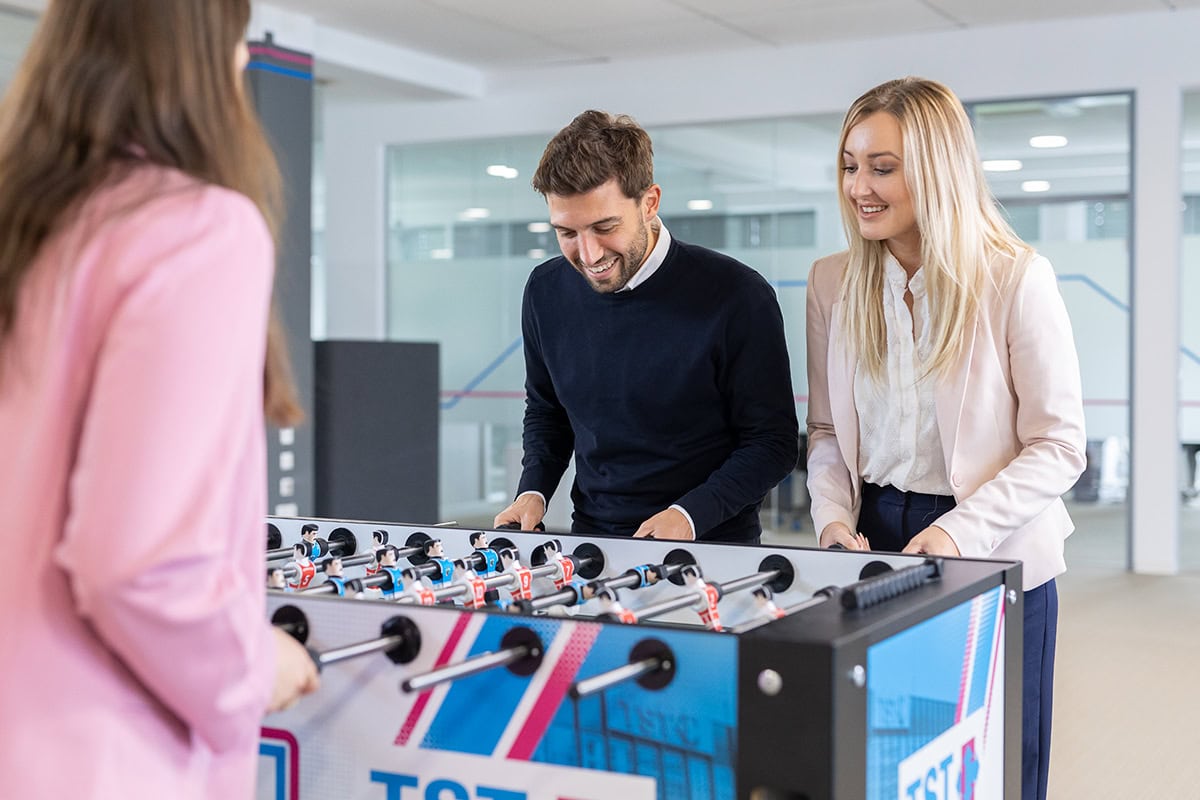 Fotografisches Portrait eines Paares beim Tischfußball in modernem Büro.