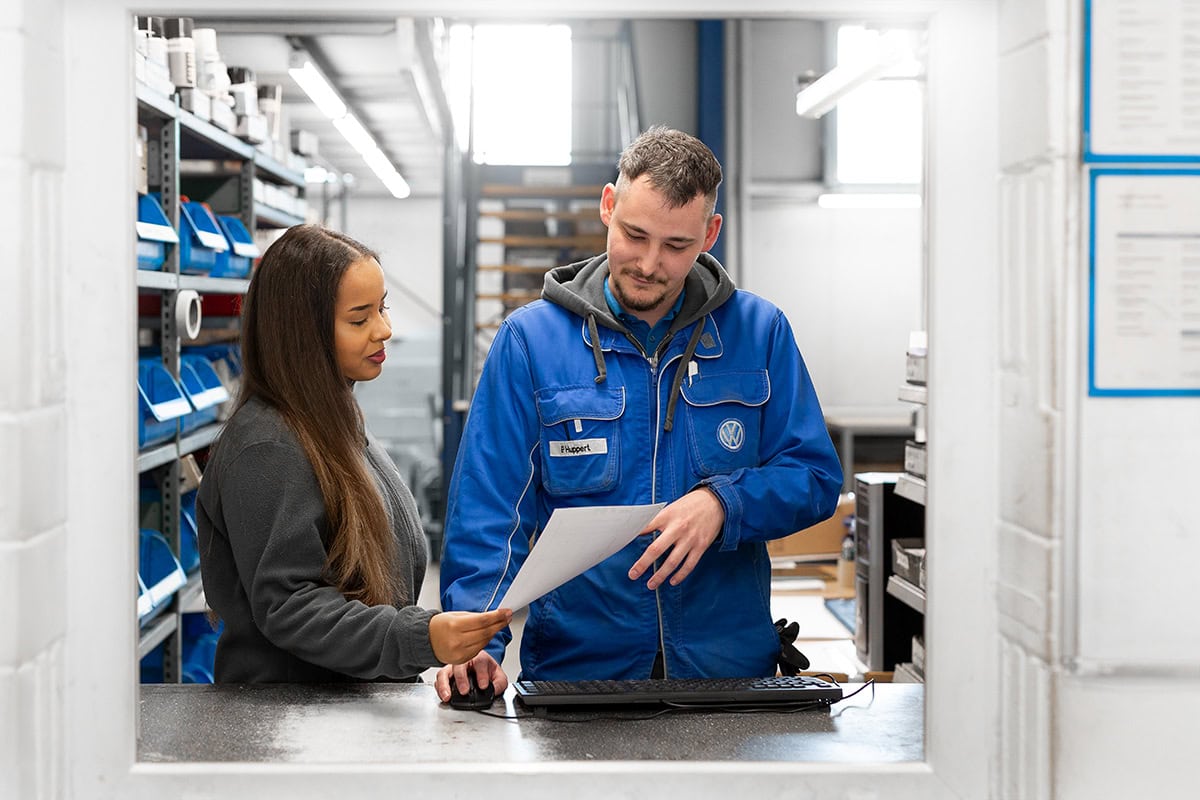 Techniker erklärt Kundin technische Details in Werkstatt, Service, Beratung.