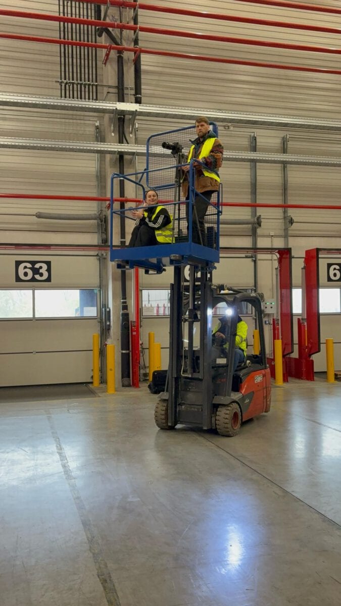 Arbeiter auf Gabelstapler in Lagerhalle bei der Inspektion der Deckeninstallation.